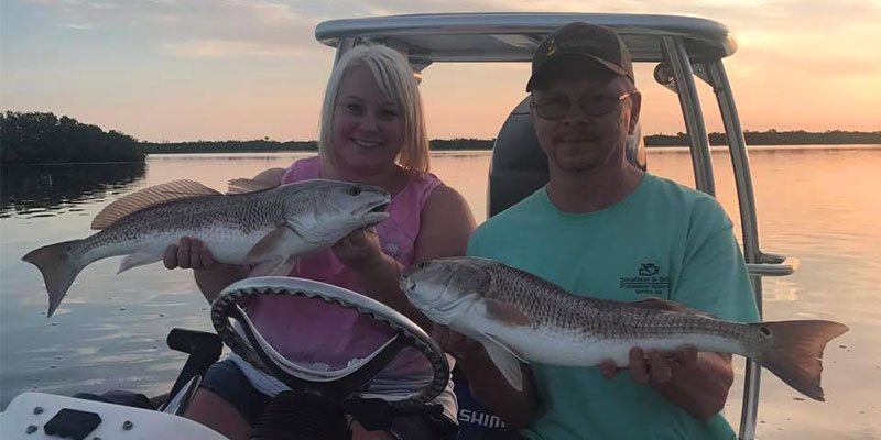 A Couple on a River Fishing Charter Holding Redfish in Port Canaveral